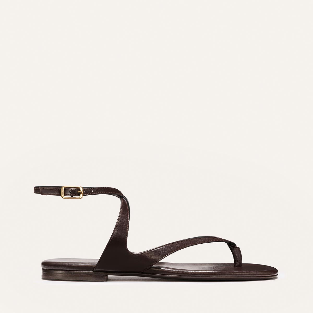 Brown sandal with a thin strap on a light beige background