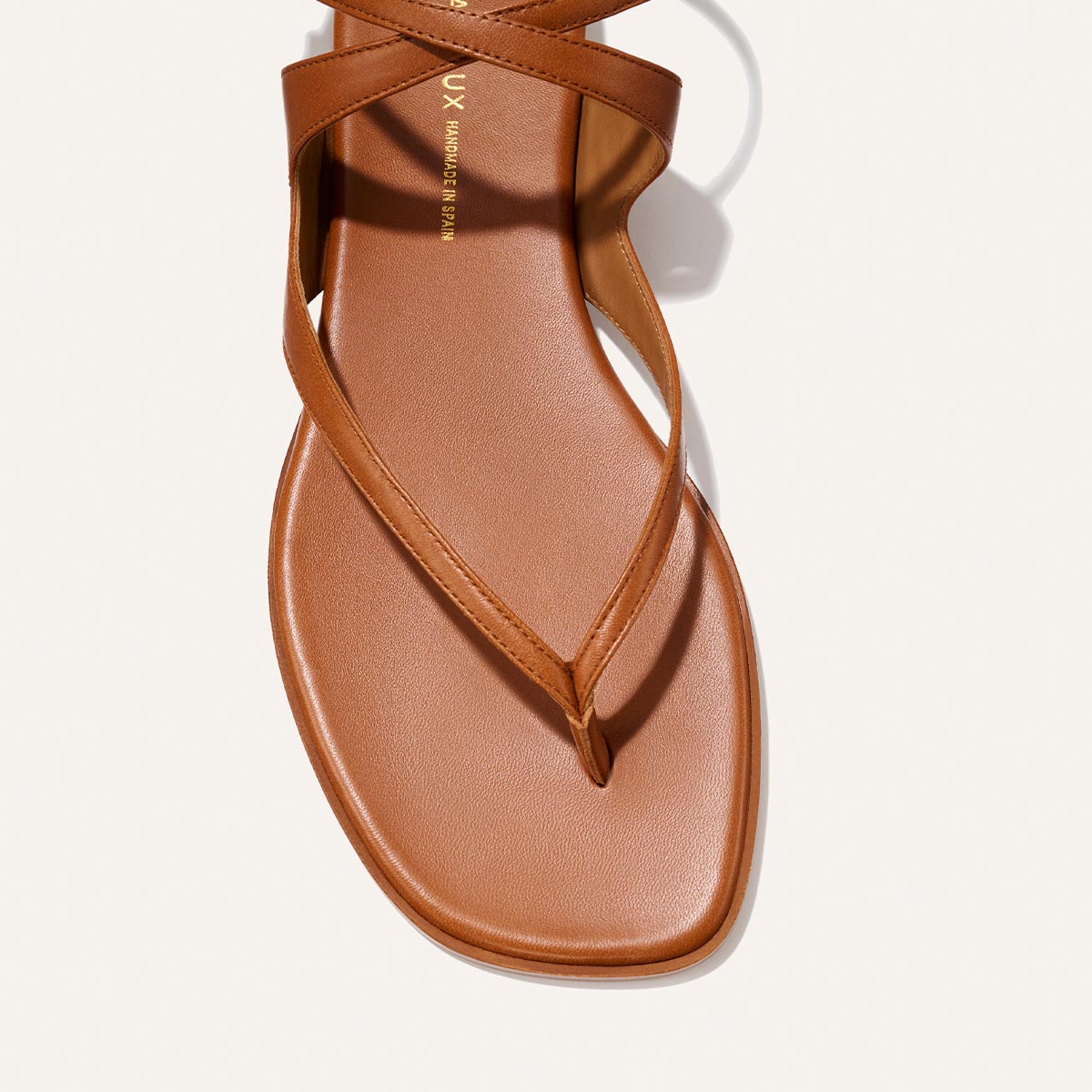 Close-up of The Palermo Sandal - Saddle Nappa by Margaux: a brown leather thong sandal with a single strap, toe loop, and cushioned insole—ideal for summer days and timeless getaway style.
