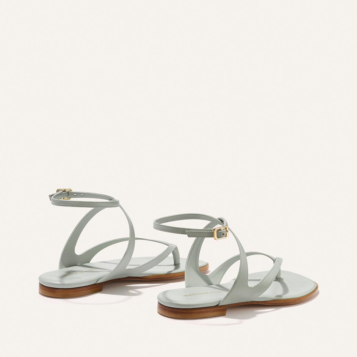 The Palermo Sandal - Sky Nappa: a pair of light blue thong-style flat sandals with cushioned insoles, ankle straps, and gold buckles.