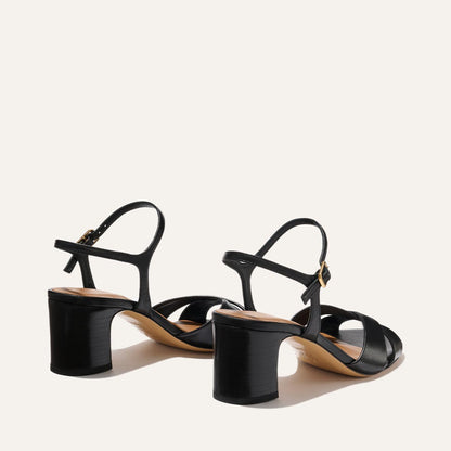 The Paloma Sandal by Margaux in Black Nappa features open toes, strappy design, medium block heels, and ankle straps, shown against a plain light background.