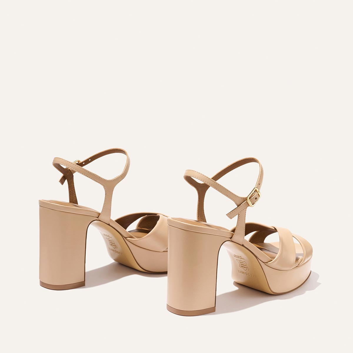 The Paloma Platform - Dune Nappa by Margaux are beige event sandals with ankle straps and block heels, shown on a light background with the heels facing the camera, designed for all-night comfort.