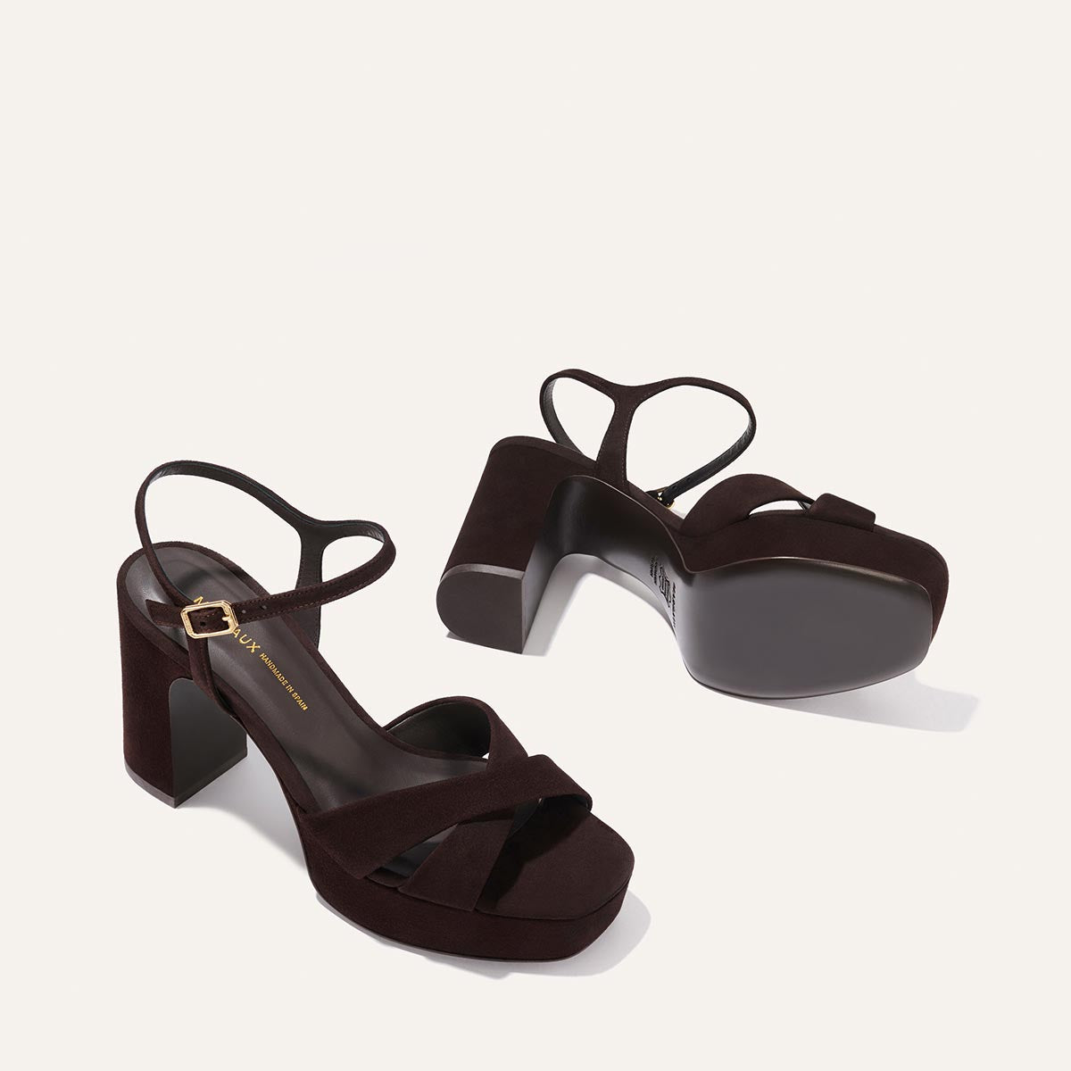 The Margaux Paloma Platform in Espresso Suede features thick block heels, padded platform soles, ankle straps, and crisscross toe straps—designed for all-night comfort. Shown on a light background: one upright, one on its side.