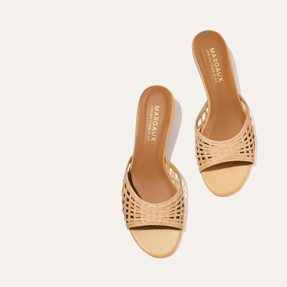 Pair of beige sandals with woven design on a white background