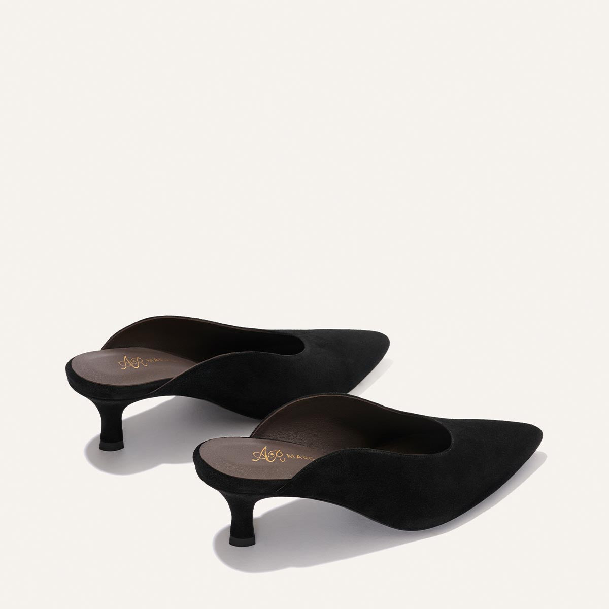 The Alison Roman x Margaux: The Parlor Mule in Black Suede by Margaux, featuring a pointed toe, low heel, and open back, is displayed on a plain light background.