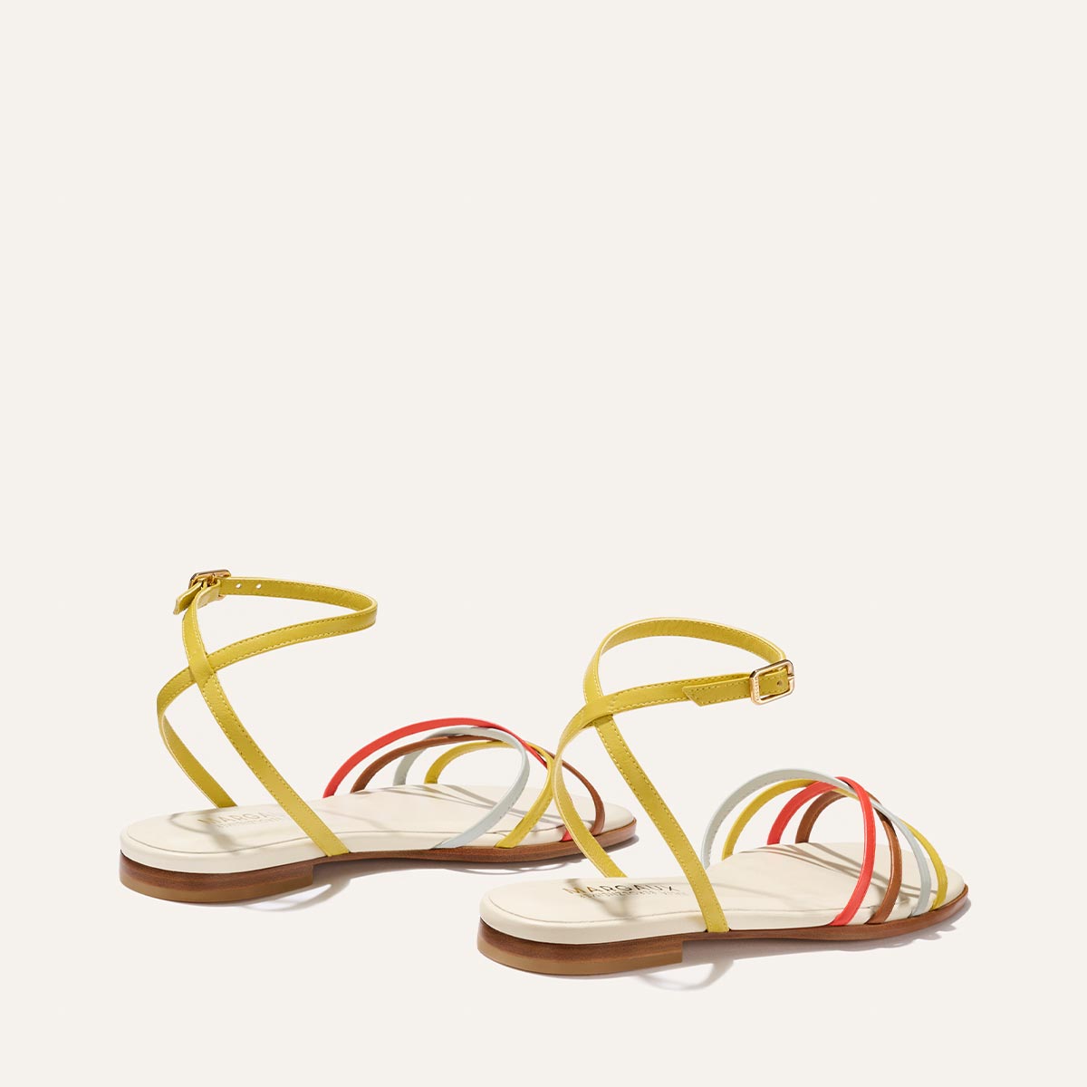 The Paros Sandal by Margaux features flat cotton and multicolor nappa design with thin yellow ankle straps and vibrant red, orange, and yellow bands—perfect for adding elevated style to your look.