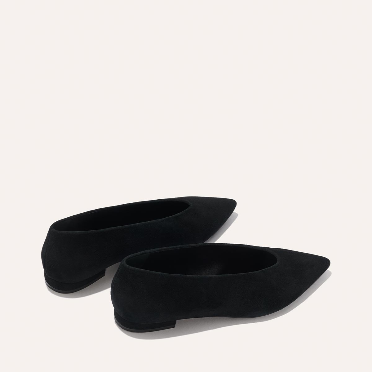The Parra - Black Suede flats by margaux-development feature a pointed toe and structured, minimalistic design, shown against a light beige background.