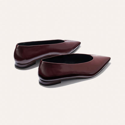 The Parra - Burgundy Calf by margaux-development: sleek, minimalist pointed-toe flats in shiny burgundy leather with low heels and a structured silhouette, shown against a plain light background.