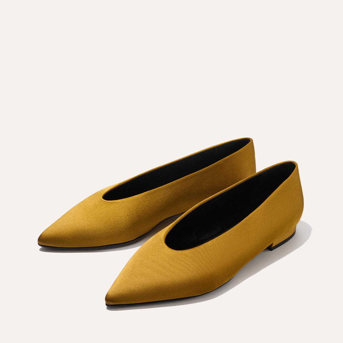 The Parra - Ochre Satin by margaux-development: pointed-toe flats in mustard yellow satin with low heels and a smooth finish, shown on a light beige background.