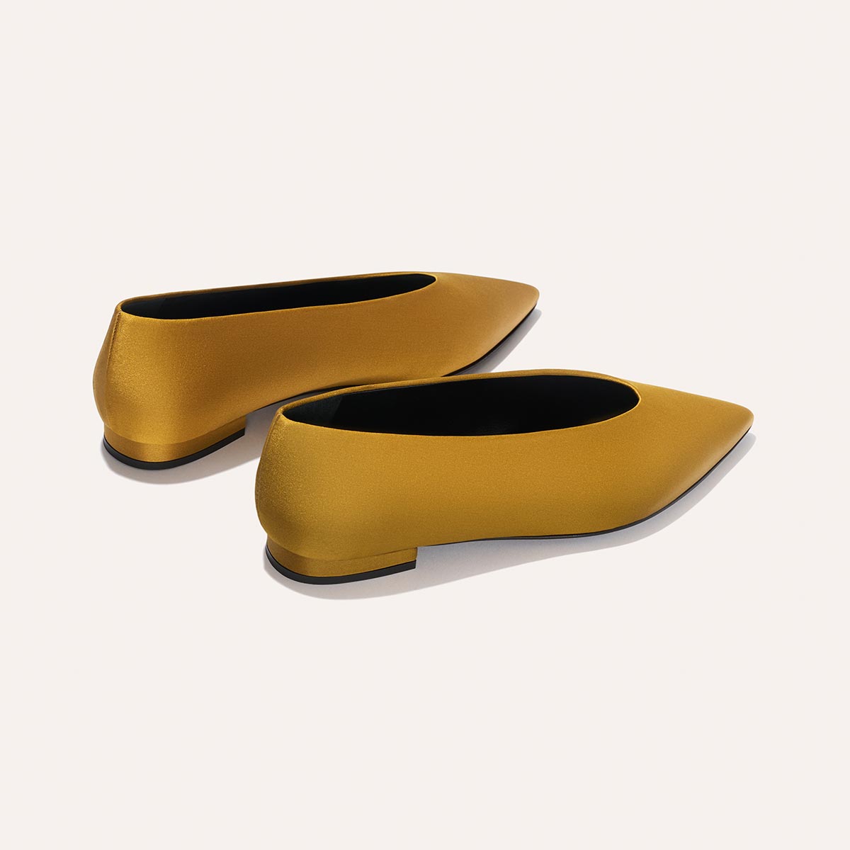 The Parra - Ochre Satin by margaux-development: a pair of pointed-toe flats in mustard yellow satin with a smooth, matte finish and low heels, displayed on a light background.