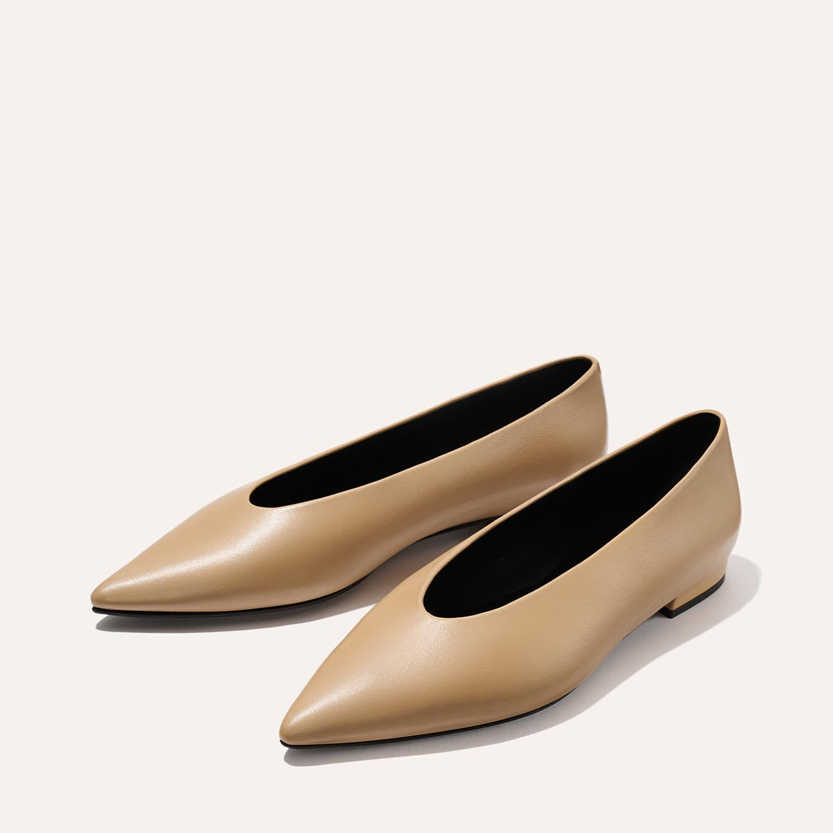 The Parra - Praline Nappa flats by margaux-development feature a beige, pointed-toe design with a high vamp and structured silhouette. Made from smooth material, these minimalist shoes offer modern style and a comfortable low heel.
