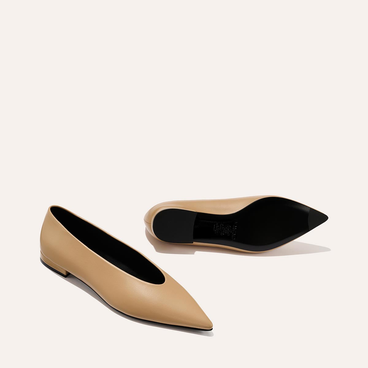 The Parra - Praline Nappa by margaux-development: beige pointed-toe flats with a high vamp and black soles, displayed on a light background—one shoe upright, the other on its side to show the sole.