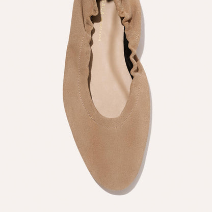 A close-up top view of Margaux's The Pascale - Cameo Suede, a tan suede flat with a rounded toe and elasticized back, photographed against a light background.