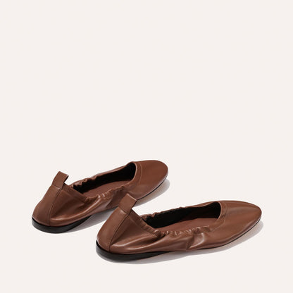 Two Pascale - Cognac Nappa ballet flats by Margaux, made of brown leather with black soles, feature an elasticized edge and heel pull tab. They are displayed on a light background.