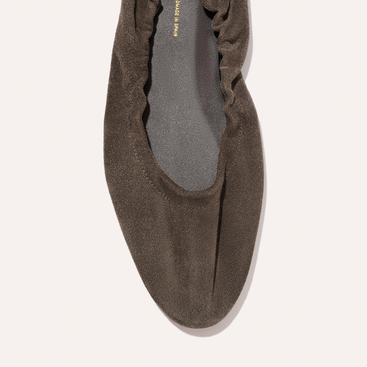 Close-up of The Pascale - English Brown Suede ballet flat by Margaux, featuring a rounded toe and gathered elasticated back around the opening, shown against a light background.