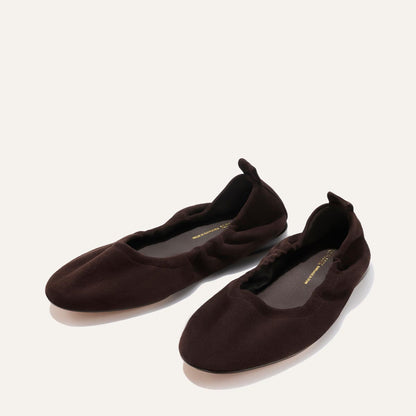 The Pascale - Espresso Suede by Margaux: a pair of dark brown suede ballet flats featuring elasticized edges and a small pull tab at the heel, displayed on a light background.
