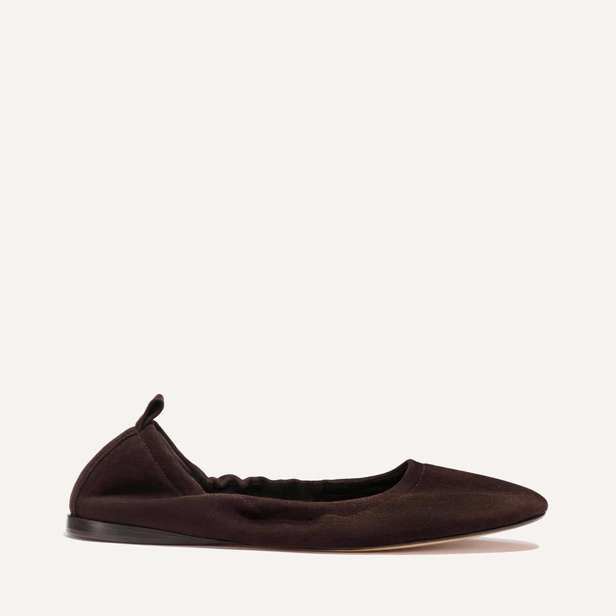 The Pascale - Espresso Suede by Margaux: a black ballet flat with a rounded toe, subtle heel, and small back loop, shown on a plain light background.