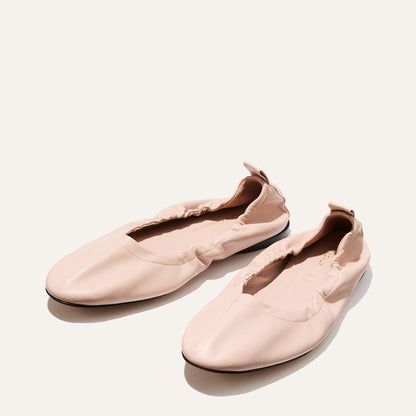 Pair of light pink loafers on a white background