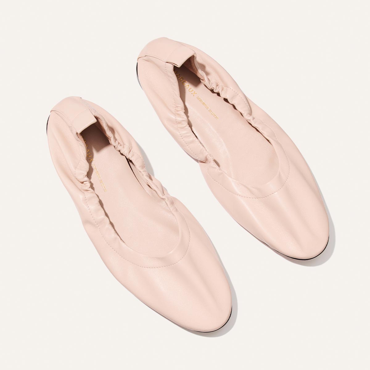 Pair of light pink loafers on a white background