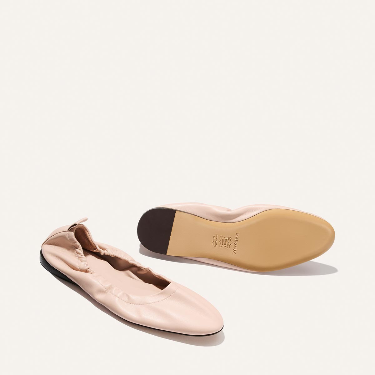 Light pink ballet flats with a focus on the sole on a white background