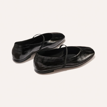 The Phoebe - Black Crinkle-Gloss Nappa by margaux-development: shiny black ballet flats with thin top straps, crafted with sacchetto construction for flexibility, shown on a plain light background.