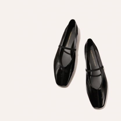 The Phoebe - Black Crinkle-Gloss Nappa by margaux-development: black leather ballet flats with sacchetto construction and a slim top strap, shown on a light beige background.