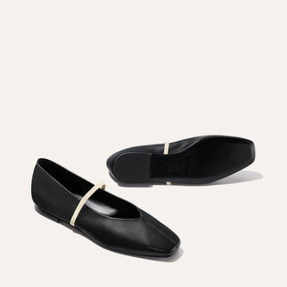 The Phoebe - Black and Ivory Nappa flats by margaux-development feature deconstructed black leather, square toes, and thin light beige straps. Displayed on a light background—one upright, the other lying on its side.