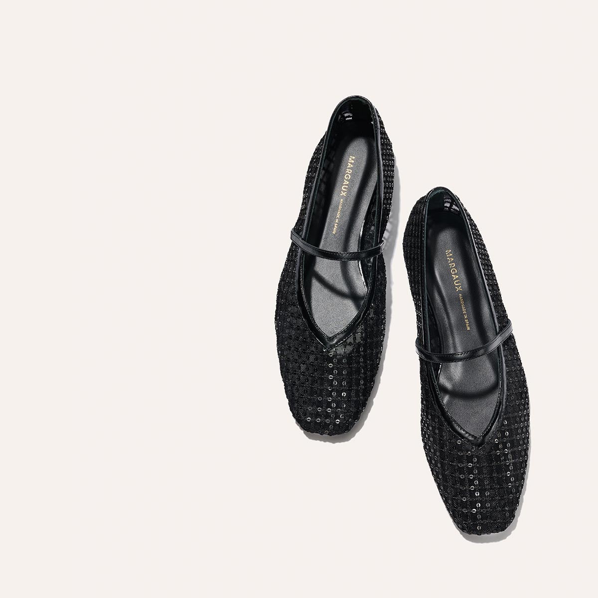 The Phoebe - Black Sequin Mesh by margaux-development: black textured Mary Jane flats with a top strap, crafted in soft deconstructed flat sacchetto construction, displayed on a plain light background.