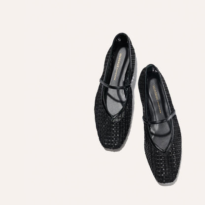 The Phoebe - Black Sequin Mesh by margaux-development: black textured Mary Jane flats with a top strap, crafted in soft deconstructed flat sacchetto construction, displayed on a plain light background.