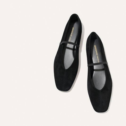 A pair of The Phoebe - Black Suede Mary Jane flats by Margaux, featuring a single thin strap across the instep, displayed on a white background.