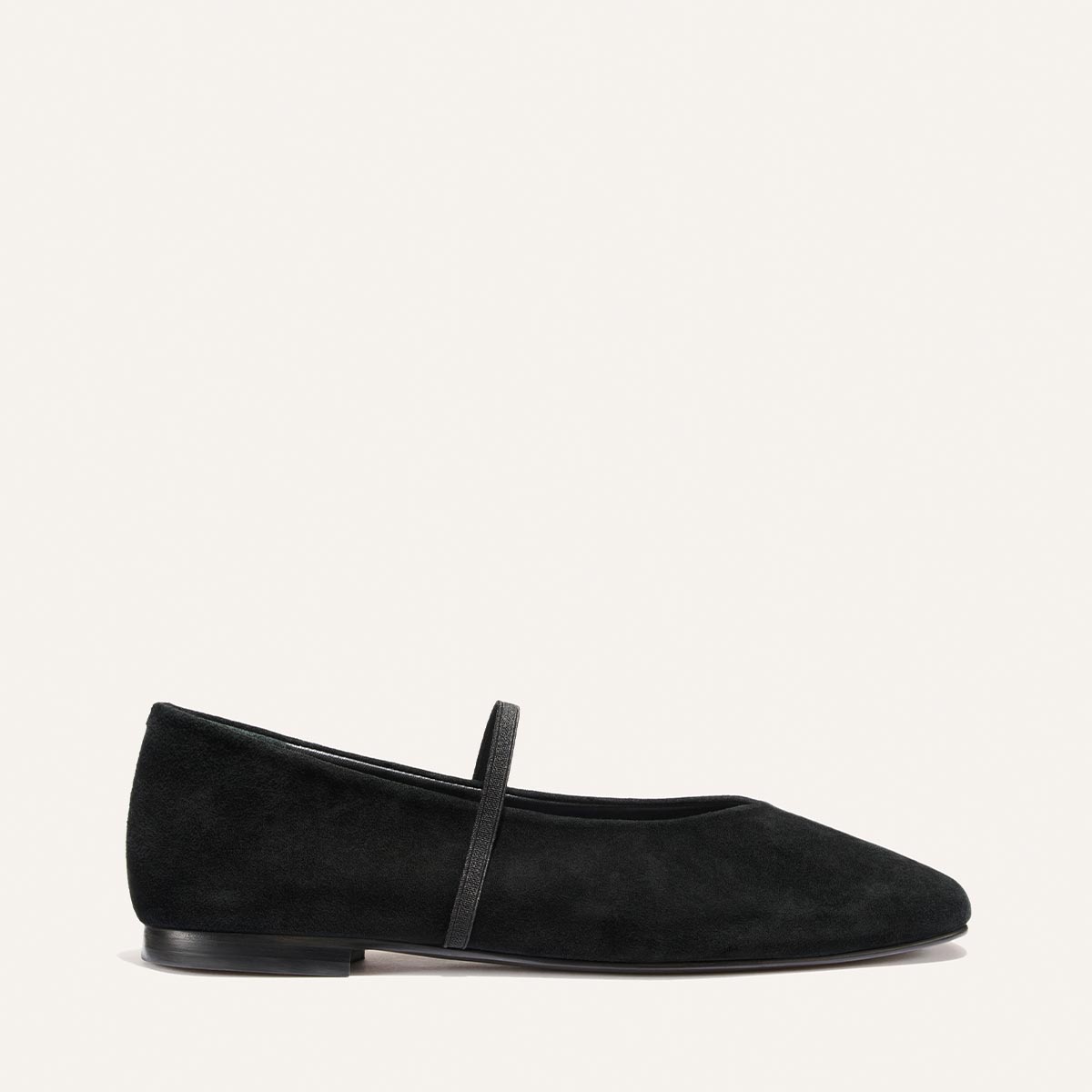 The Phoebe - Black Suede by Margaux is a black suede ballet flat featuring a thin strap across the instep, a low heel, and a rounded toe, shown against a plain white background.