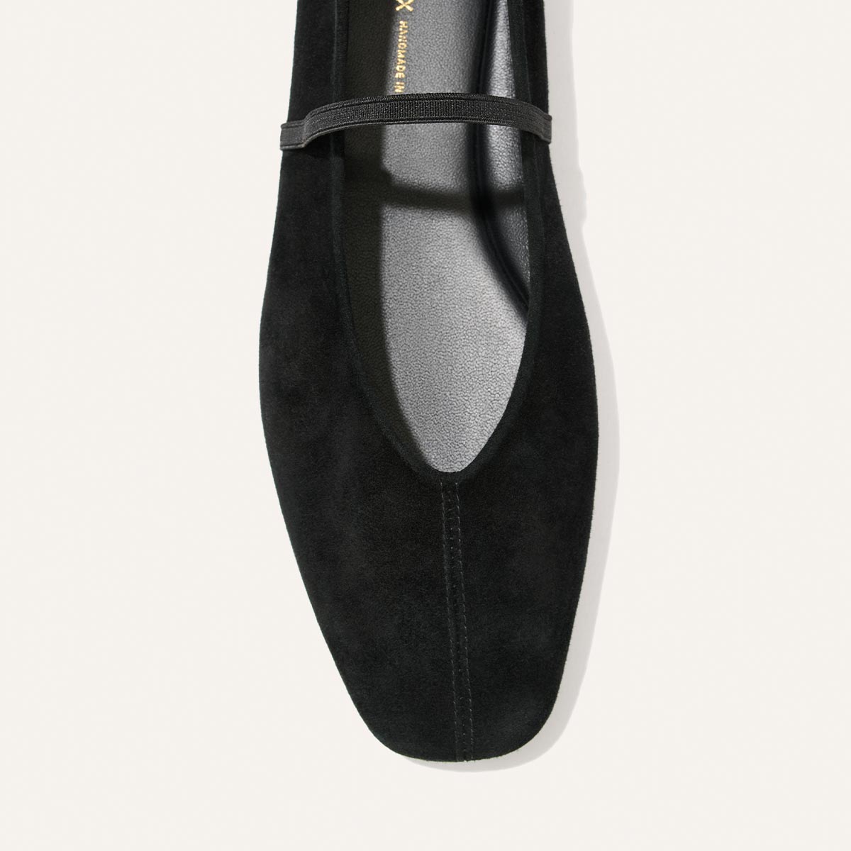 A top-down view of The Phoebe - Black Suede by Margaux, a black suede Mary Jane flat featuring a thin strap across the top and a subtly squared toe, set against a white background.