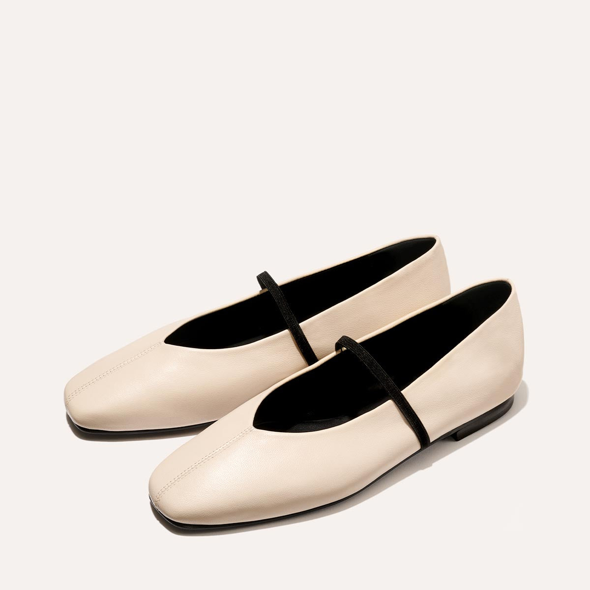 The Phoebe in smooth Bone Nappa leather, a ballet flat with a squared off toe, high vamp and elastic Mary Jane strap.