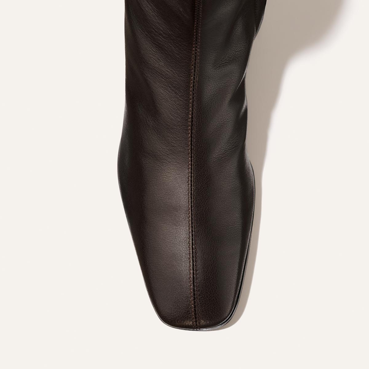 Top view of The Phoebe Boot - Dark Chocolate Calf by Margaux, a dark brown leather boot with a square toe and center-front detailed stitching, featuring a stacked leather heel, shown against a light background.