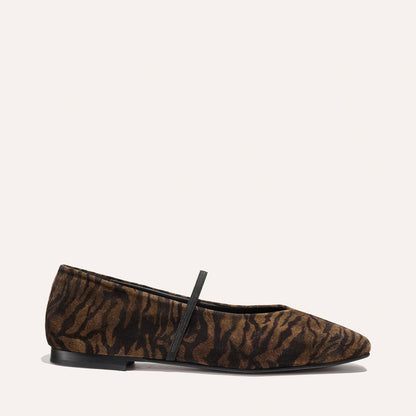 The Phoebe - Brown Zebra Suede by Margaux is a flat shoe featuring a brown and black zebra pattern, a black elastic front strap, and a low black sole, shown against a plain light background.