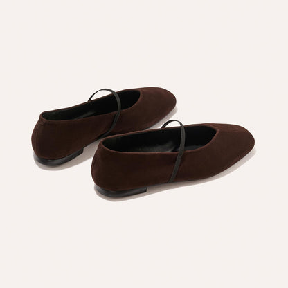The Phoebe - Espresso Suede by margaux-development are dark brown suede Mary Jane flats featuring thin black straps, black soles, a square toe, and sacchetto construction for extra comfort, shown against a light background.