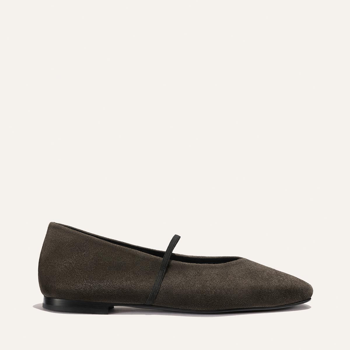 A single Graphite Suede flat from Margaux, The Phoebe, crafted with traditional sacchetto construction for exceptional comfort, features a thin black strap across the top and is displayed on a plain light background.