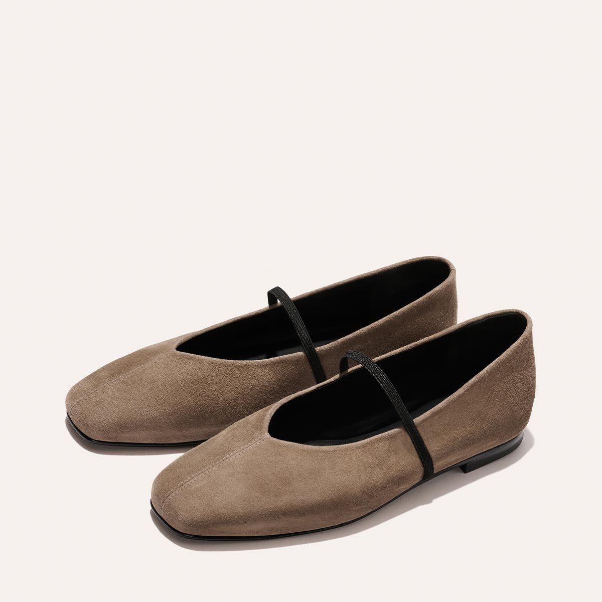 Margaux's The Phoebe in mushroom suede: taupe ballet flats with square toes and black elastic straps, shown on a light background.