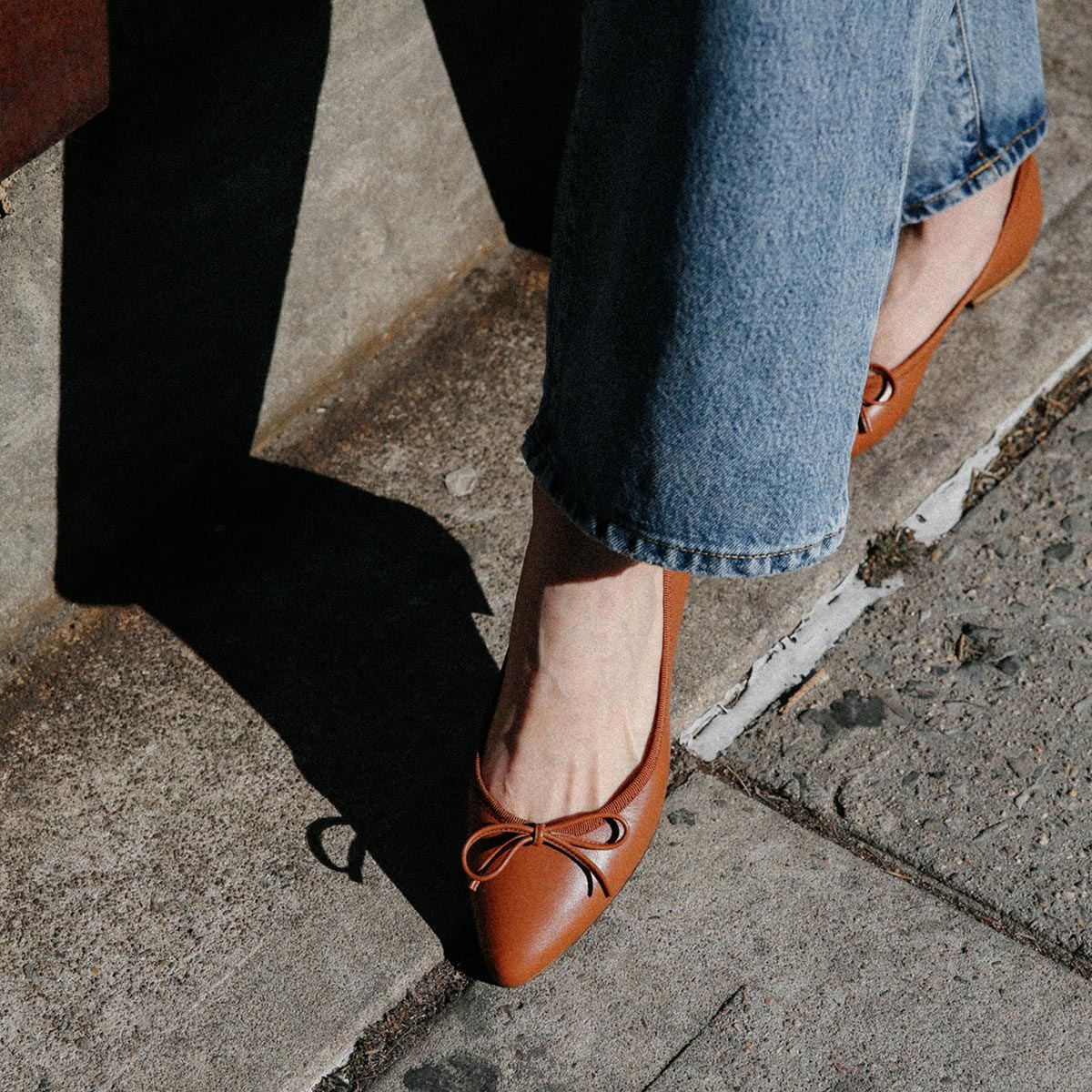 The Pointe in Saddle Nappa, a classic and comfortable ballet flat featuring a refined pointed toe design and decorative bow. 