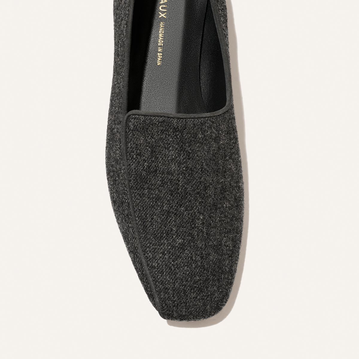 Close-up, top-down view of a charcoal grey wool Portia Loafer - Grey Flannel with black piping.