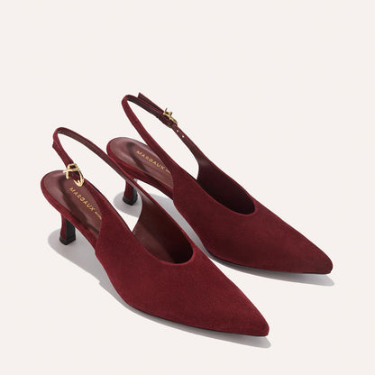 The Prado Sling - Burgundy Suede by margaux-development features elegant pointed-toe slingback heels in deep burgundy suede with low heels and gold buckle accents on the ankle straps, displayed on a light background.