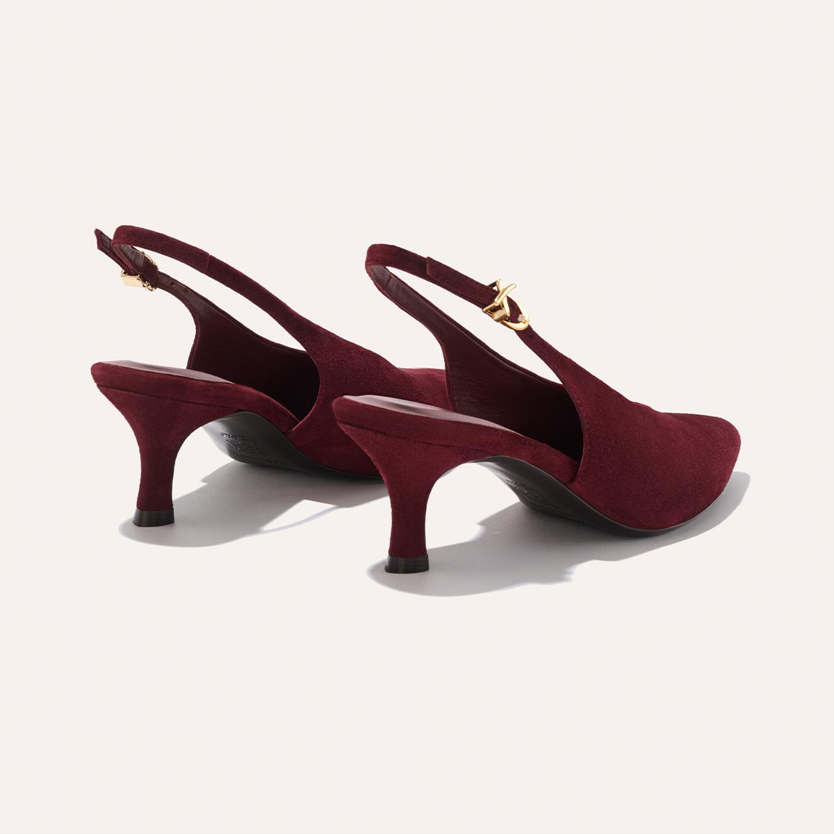 The Prado Sling - Burgundy Suede by margaux-development: elegant dark red suede slingback heels with pointed toes, mid-height heels, gold buckle straps, and black soles, displayed on a light background.