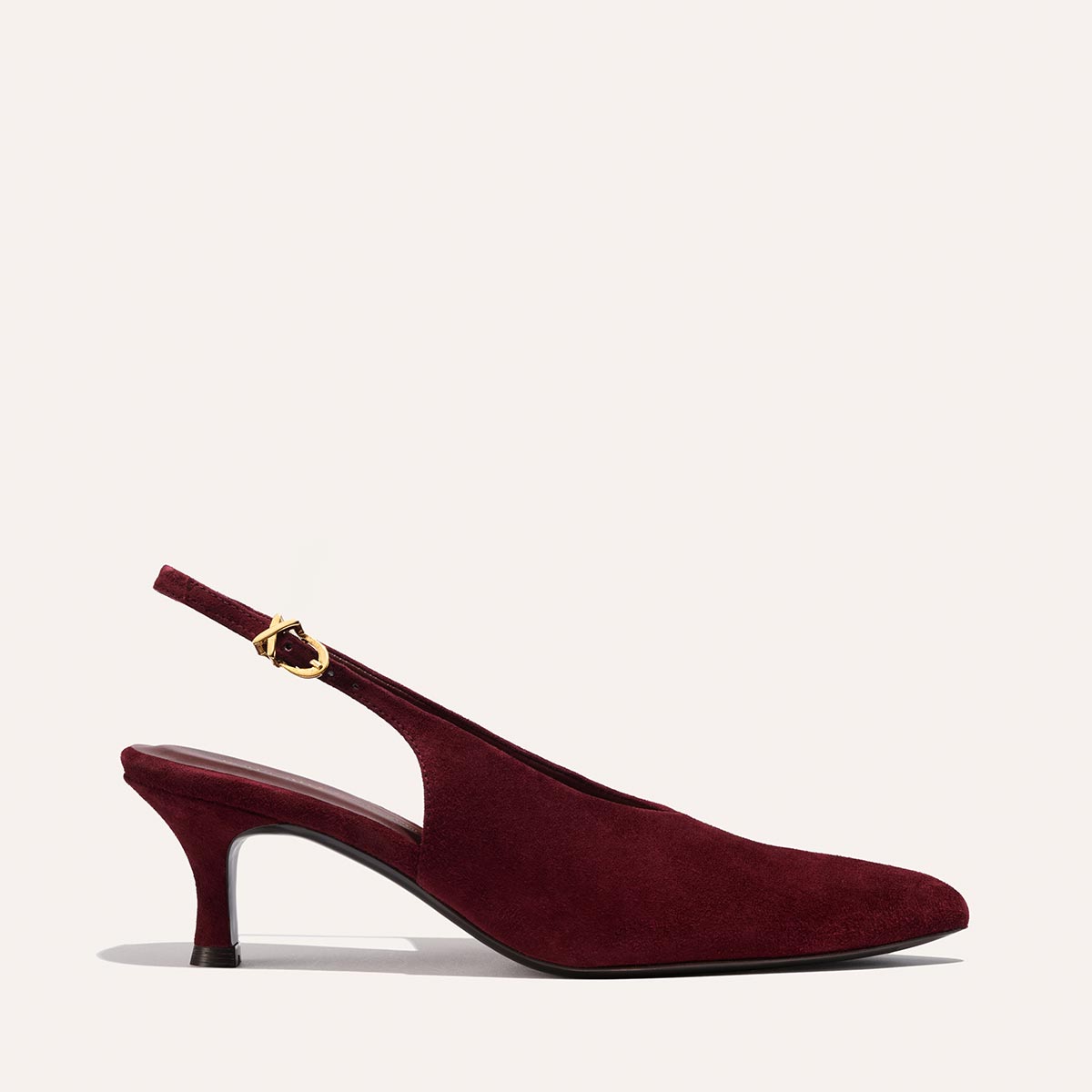 The Prado Sling by margaux-development is a burgundy suede slingback pump with a pointed toe, low heel, and gold buckle on the adjustable strap, shown against a light background.