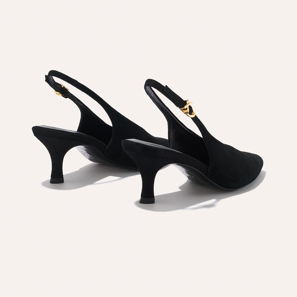 The Prado Sling - Black Suede by margaux-development: black slingback heels with pointed toes, mid-height heels, and gold buckle straps, shown against a plain light background.
