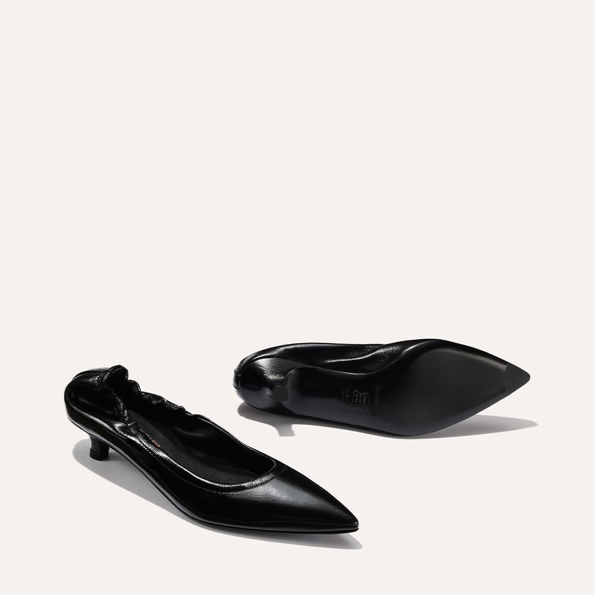 The Margaux Roma 40 - Black Crinkle Patent shoes are shown on a light background, with one pointed-toe kitten heel upright and the other on its side.