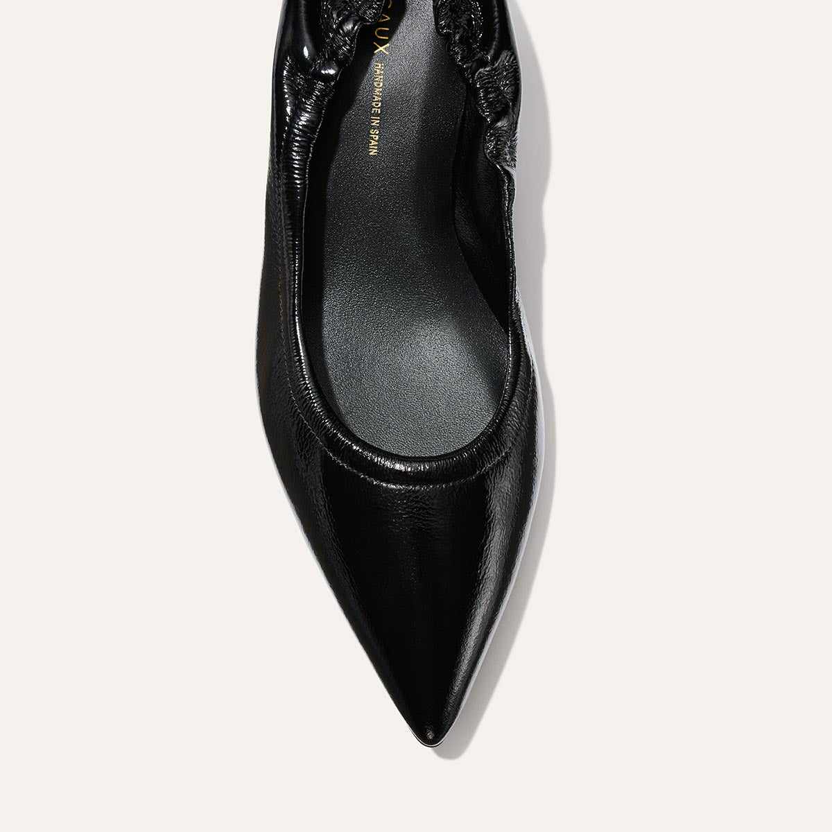 A close-up top view of Margaux's The Roma 40 - Black Crinkle Patent, a pointed-toe flat with a gathered elastic heel, displayed against a plain light background.