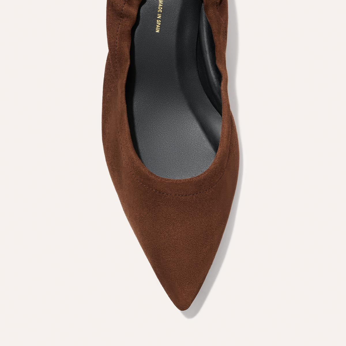 A top view of the Margaux The Roma 40 - Ganache Suede, a brown pointed-toe flat with a gathered edge and black insole, displayed on a light background.