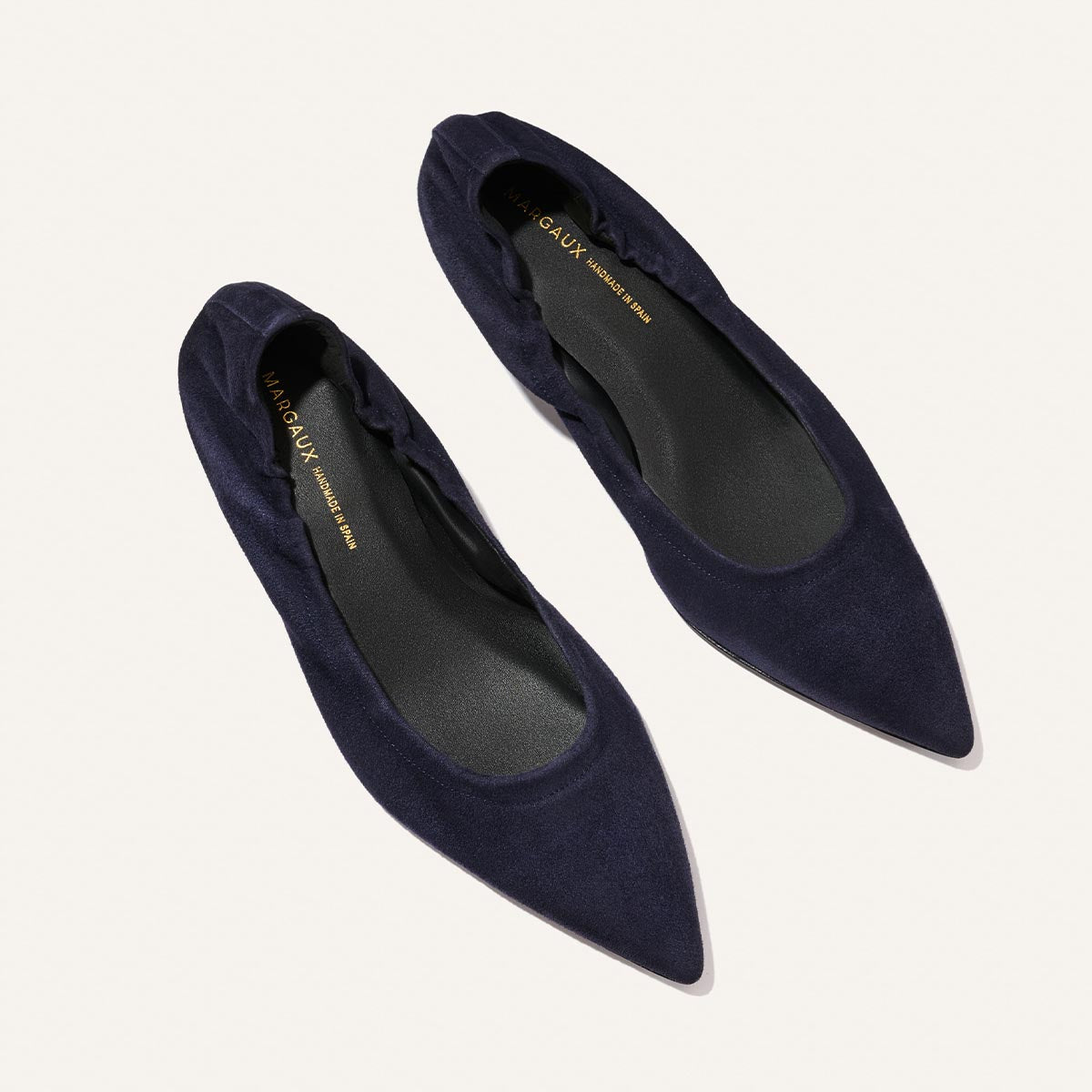 A pair of Margaux’s The Roma 40 flats in indigo suede, featuring a pointed toe, ruched heel detail, and a comfortably walkable heel, displayed on a light background.