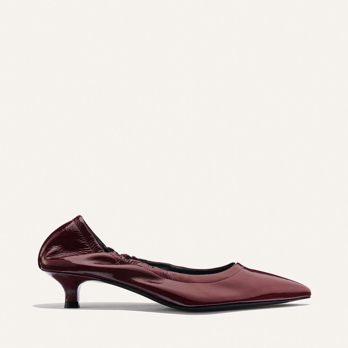 The Roma 40 - Merlot Crinkle Patent by Margaux is a maroon patent leather kitten heel shoe featuring a comfortable, walkable heel, ruched back detail, and a sleek pointed toe, shown against a simple light background.