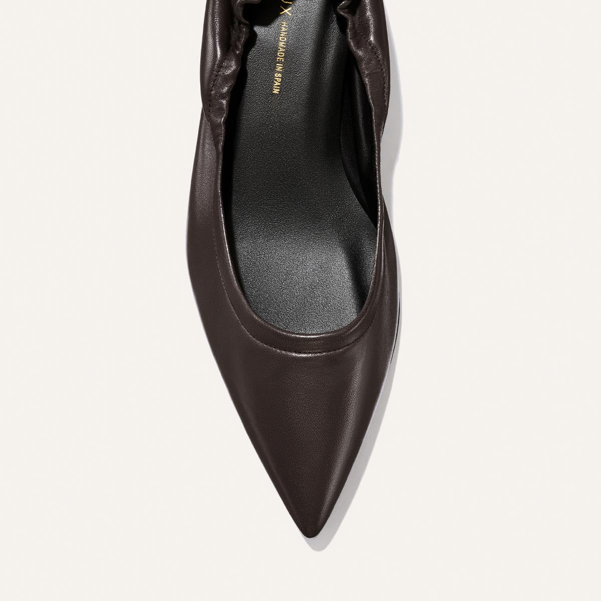 A top view of The Roma 40 - Espresso Nappa by Margaux, a chic pointed-toe flat in dark brown leather featuring a gathered ruched back and a black insole, set against a plain light background.