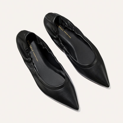 The Roma - Black Nappa by Margaux are elegant black pointed-toe ballet flats with ruched detailing, combining classic style and comfort, shown on a light background.